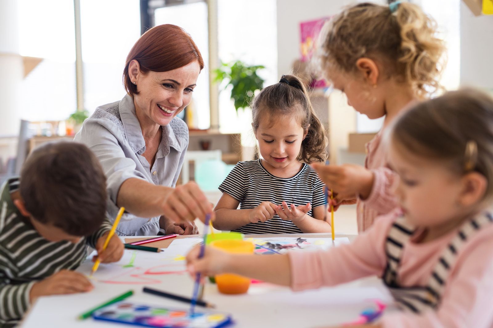 Pädagogische Fachkraft begleitet Kinder beim gemeinsamen Lernen.