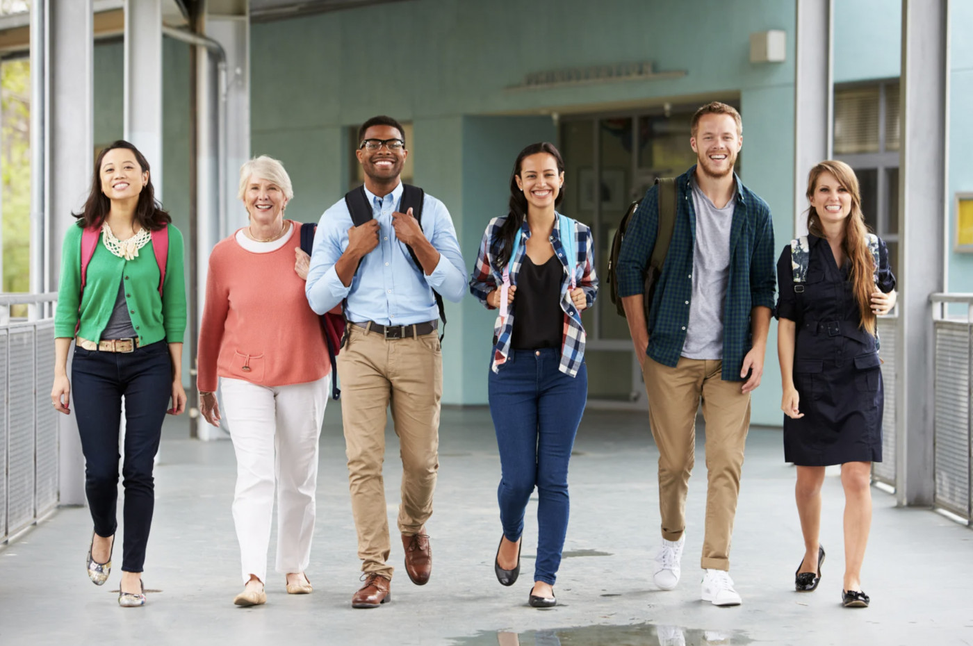 Eine Gruppe erwachsener Lernender geht gemeinsam über einen Campus.